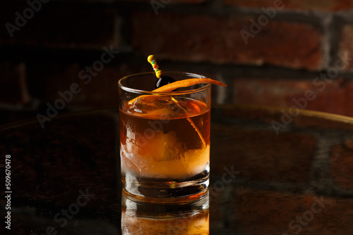 Obraz na płótnie Crystal glass with bright cold alcoholic cocktail decorated with orange zest. Blurred background. Negroni cocktail. w salonie