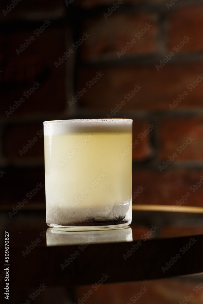 Pisco sour cocktail - whiskey with lime, egg white, sugar syrup in glass on dark background. Space for text
