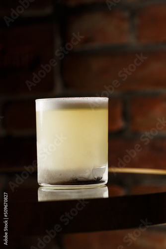 Obraz na płótnie Pisco sour cocktail - whiskey with lime, egg white, sugar syrup in glass on dark background. Space for text w salonie