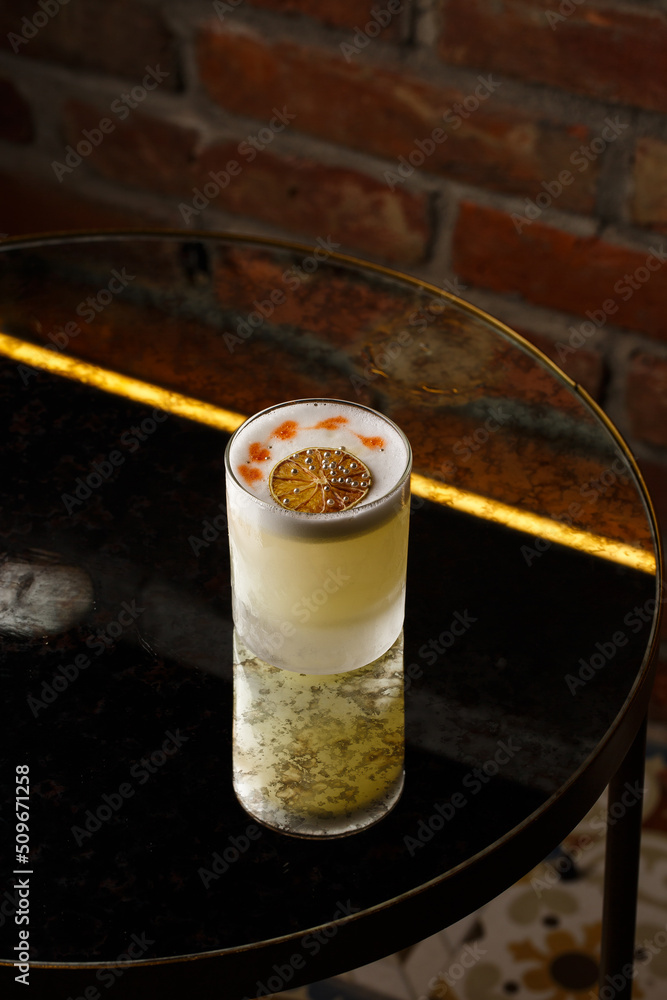 Pisco sour cocktail - whiskey with lime, egg white, sugar syrup in glass on dark background. Space for text