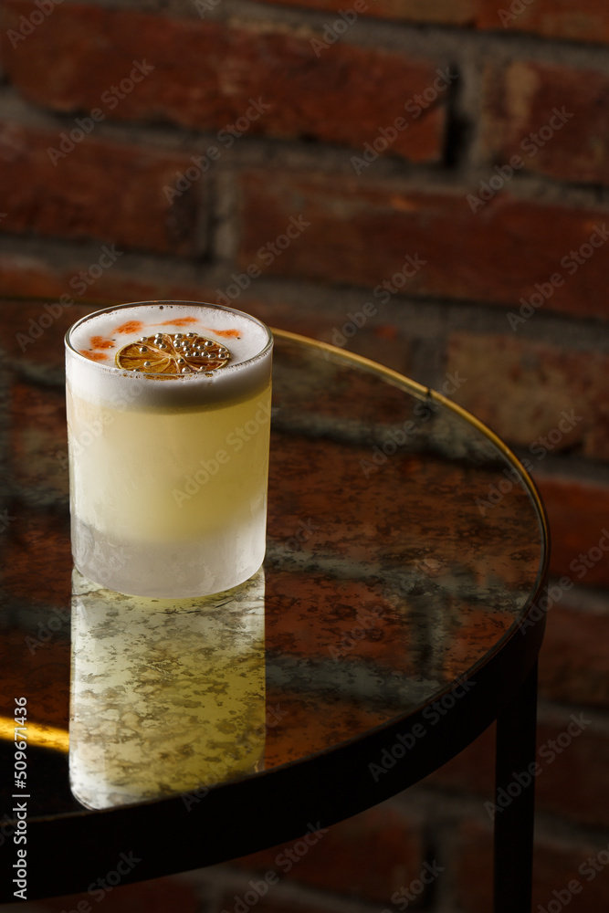 Pisco sour cocktail - whiskey with lime, egg white, sugar syrup in glass on dark background. Space for text