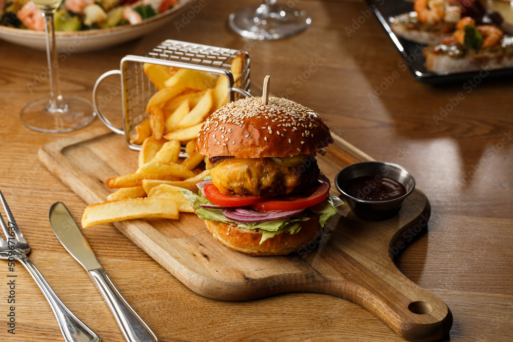 Big cheeseburger with french fries isolated on white background. Hamburger with beef patty onion, tomato, lettuce pickles, melted cheddar, mustards, tomato jam, mayo