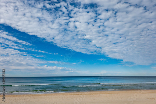 Surfer s Paradise beach to sea and horizon with white soft clouds formation
