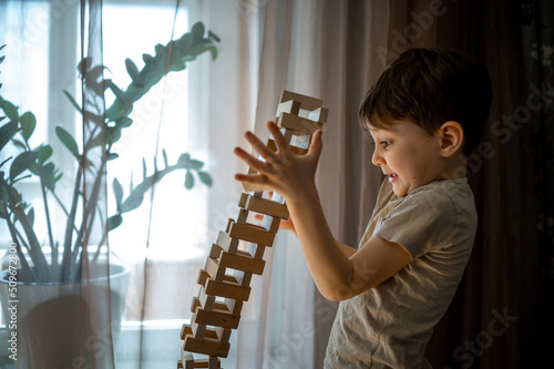 a boy builds a tower out of wooden blocks at home