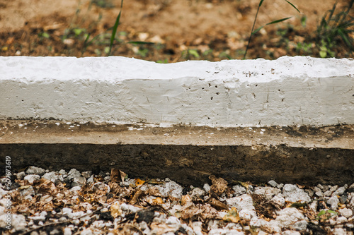 Close-up of a whitewashed, white-painted curb, border at the edge of a road. © shchus