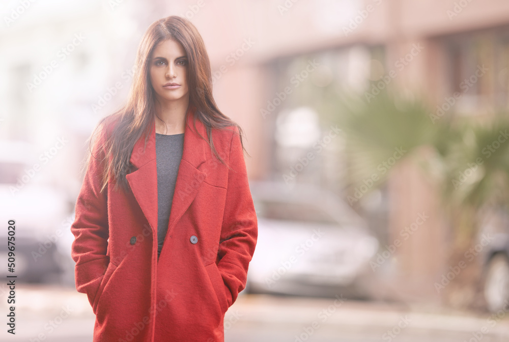 Look fab this fall. Portrait of a gorgeous young woman in a red winter coat standing in an urban setting.