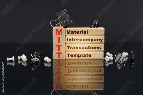 On a black reflective surface, wooden blocks with the inscription - Material Intercompany Transactions Template photo