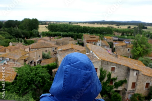woman with a blue hood in front of a town