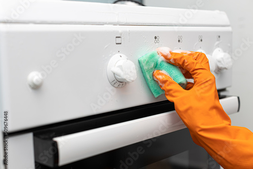 woman in rubber gloves wipes the gas stove