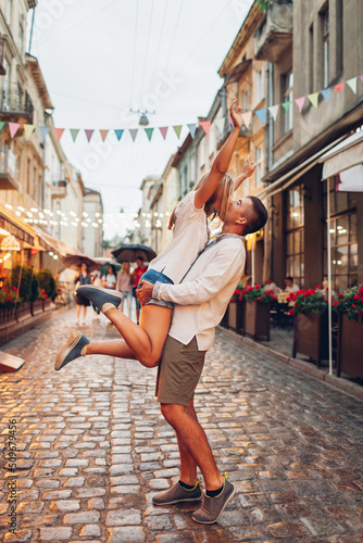 Couple in love walking in old Lviv city wearing traditional ukrainian shirts. Man raising woman having fun outdoors