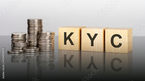 kyc - text on wooden cubes on a cold grey light background with stacks coins photo