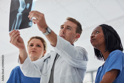 Consulting his colleagues for a second opinion. Cropped shot of a group of medical practitioners viewing an x-ray together.