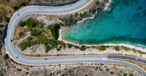 Fototapeta Naklejka Na Ścianę i Meble -  Top view of a beautiful beach with turquoise sea surounded by a street with traffic as seen in Varkiza, Attica Greece