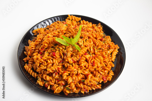 auger pasta on black plate on white background