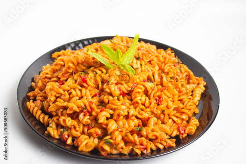 auger pasta on black plate on white background