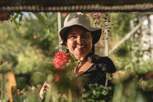 Foto Short, heavy-set Latina woman working in her botanical garden with a hat on her head, very happy