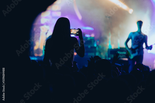 Silhouette of a woman using smartphone on a concert