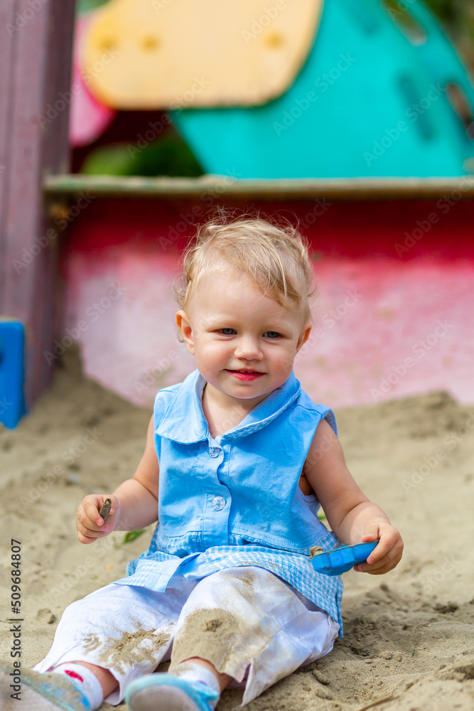 Girl playing with toys in the sandbox in the yard Girl playing with toys in the sandbox in the yard