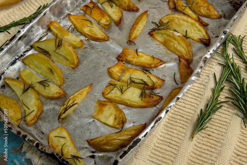 Portion of roasted potato, seasoned with rosemary, on rustic wooden table photo