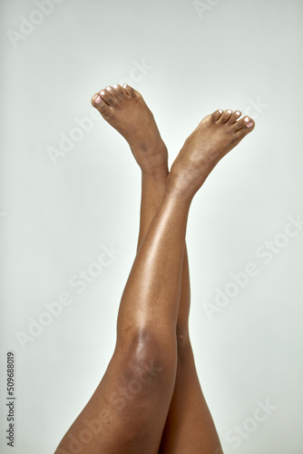 African american female crossed legs raised up. Fat hips. Skin care, spa and pedicure. Body positive concept photo