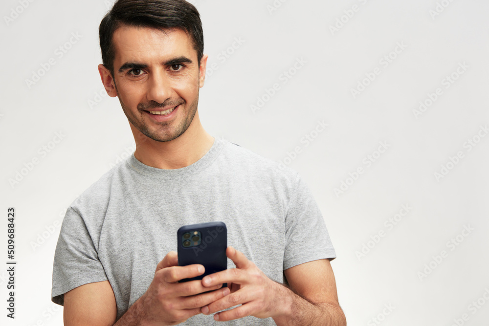 portrait man in a gray t-shirt with a phone communication technology isolated background portrait man in a gray t-shirt with a phone communication technology isolated background