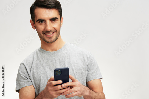 portrait man in a gray t-shirt with a phone communication technology isolated background © SHOTPRIME STUDIO