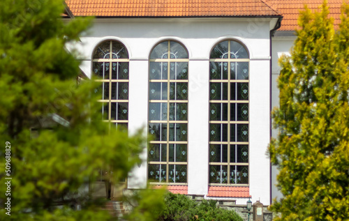 Colorful stained glass window on a summer sunny day surrounded by greenery © Sviatlana