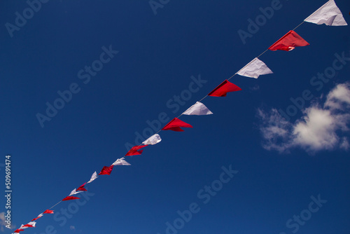 Bandeirolas penduradas por fio com céu azul ao fundo.