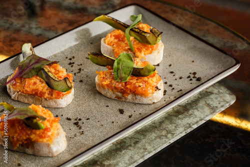 Obraz na płótnie baked bruschetta with salmon, cheese, sun-dried tomatoes and avocado in gray plate on bright background w salonie