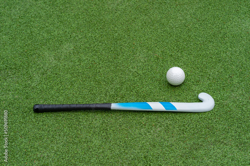 Field hockey stick and ball on green grass. Horizontal sport theme poster, greeting cards, headers, website and app