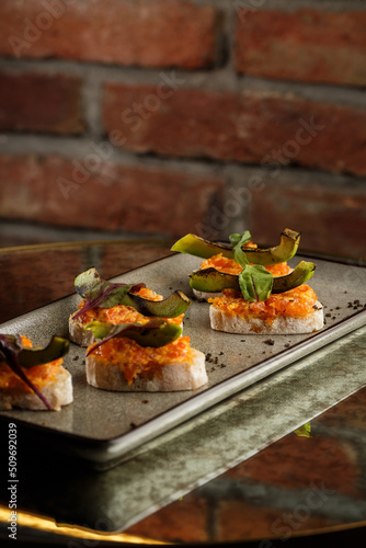 Obraz na płótnie baked bruschetta with salmon, cheese, sun-dried tomatoes and avocado in gray plate on bright background w salonie