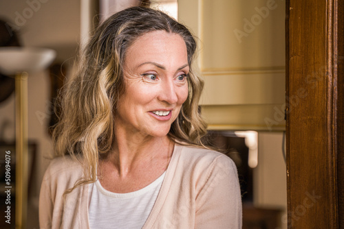 Cheerful adult woman looking away with happy smile while chatting with somebody