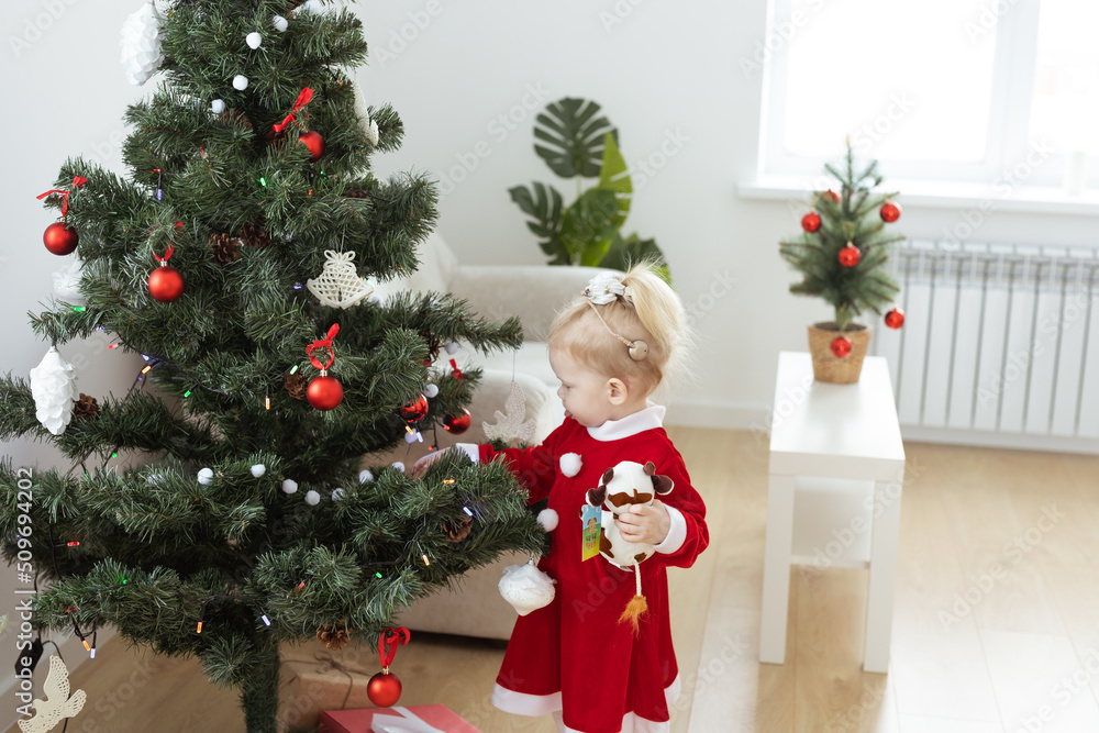 Toddler child with cochlear implant decorating christmas tree - deafness and diversity and innovating medical technologies for hearing aid Toddler child with cochlear implant decorating christmas tree - deafness and diversity and innovating medical technologies for hearing aid