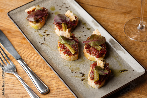 Four bruschettas with beef tartare on a plate, Crostini with Beef Tartare, beef Bruschetta, sandwich with raw gourmet beef.