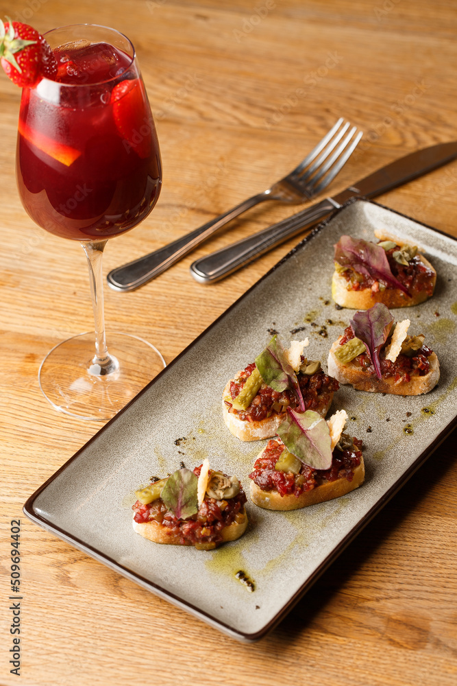 Four bruschettas with beef tartare on a plate, Crostini with Beef Tartare, beef Bruschetta, sandwich with raw gourmet beef.