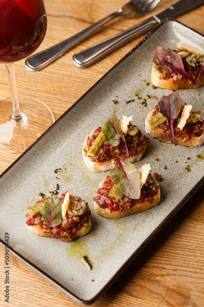 Four bruschettas with beef tartare on a plate, Crostini with Beef Tartare, beef Bruschetta, sandwich with raw gourmet beef.