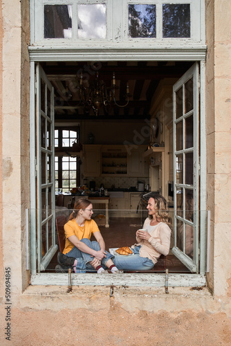 Cheerful woman talking with her teenage daughter during the breakfast