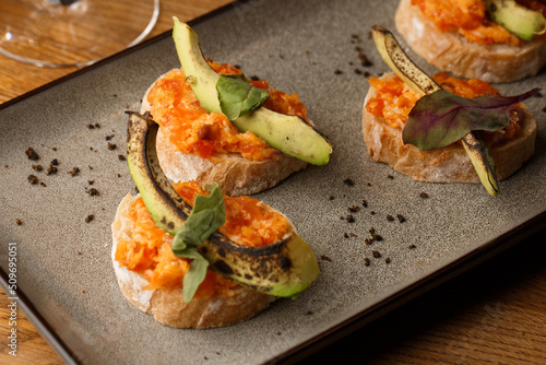 Obraz na płótnie baked bruschetta with salmon, cheese, sun-dried tomatoes and avocado in gray plate on bright background w salonie