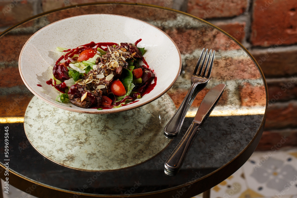 Salad with veal and tomatoes. Beef steak with raw vegetables mix side view. Grilled meat with garnish close-up. Delicious main course on table