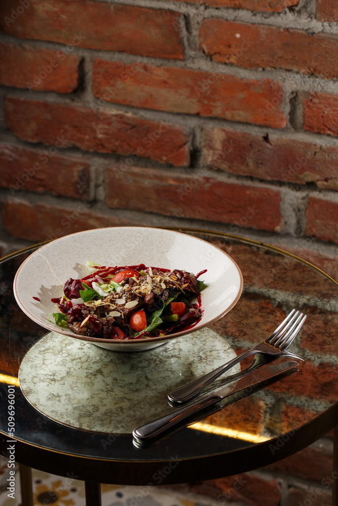 Salad with veal and tomatoes. Beef steak with raw vegetables mix side view. Grilled meat with garnish close-up. Delicious main course on table