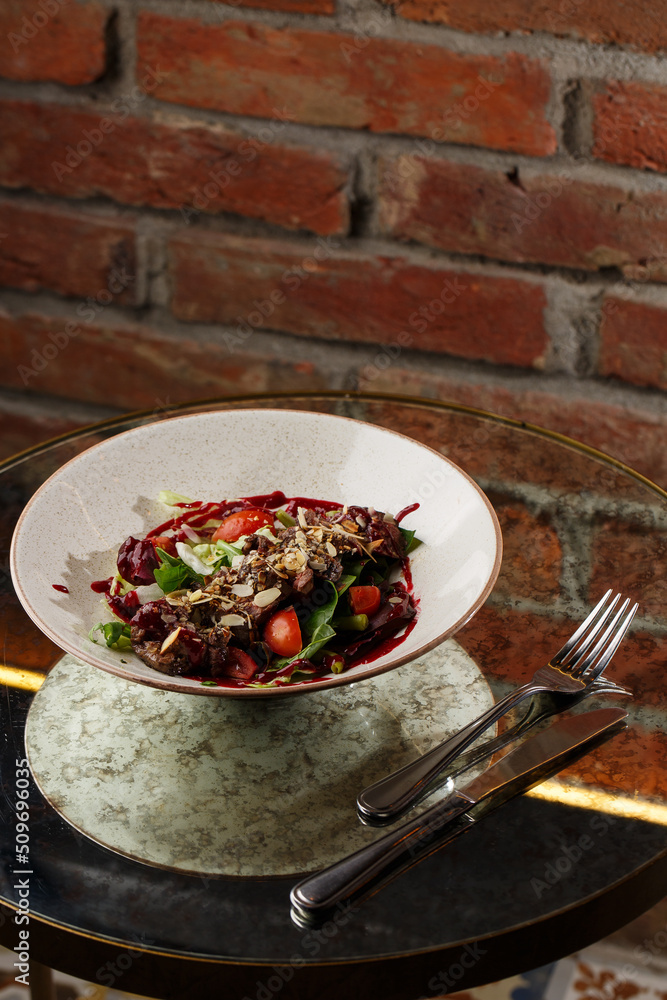 Salad with veal and tomatoes. Beef steak with raw vegetables mix side view. Grilled meat with garnish close-up. Delicious main course on table