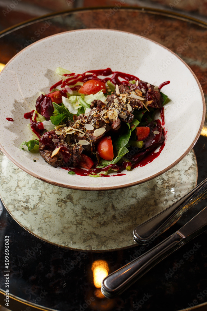 Salad with veal and tomatoes. Beef steak with raw vegetables mix side view. Grilled meat with garnish close-up. Delicious main course on table