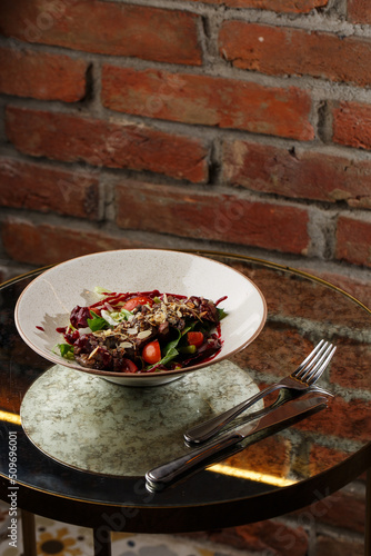 Obraz na płótnie Salad with veal and tomatoes. Beef steak with raw vegetables mix side view. Grilled meat with garnish close-up. Delicious main course on table w salonie