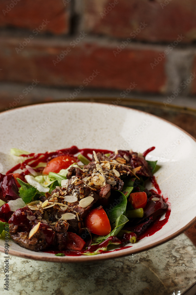 Salad with veal and tomatoes. Beef steak with raw vegetables mix side view. Grilled meat with garnish close-up. Delicious main course on table
