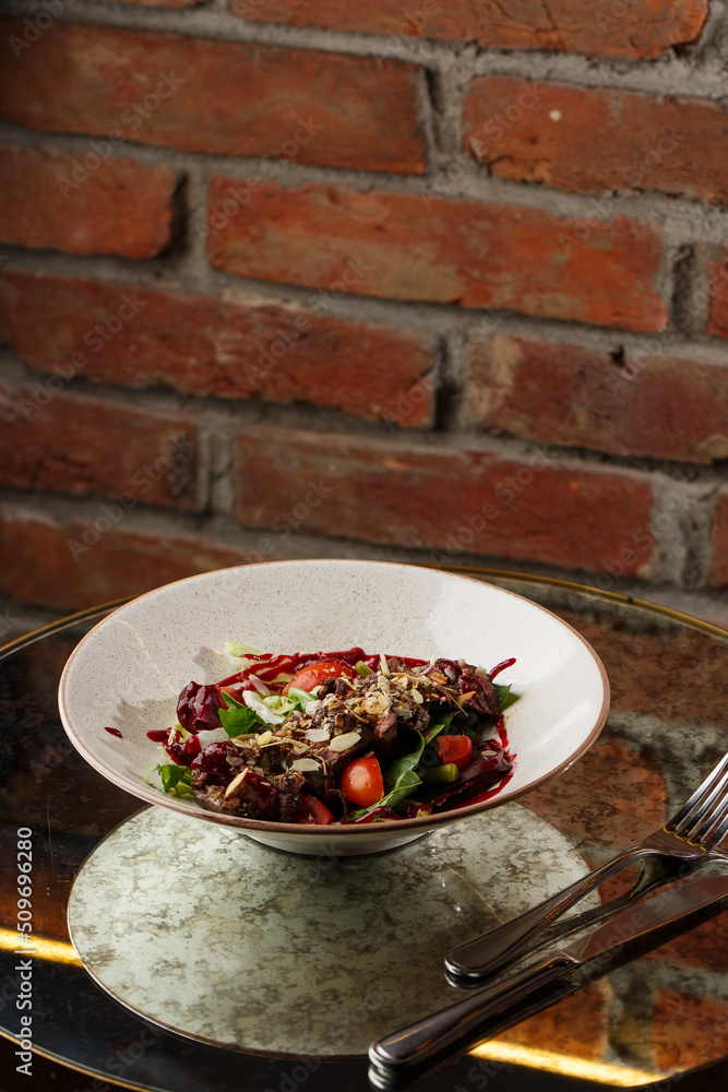Salad with veal and tomatoes. Beef steak with raw vegetables mix side view. Grilled meat with garnish close-up. Delicious main course on table