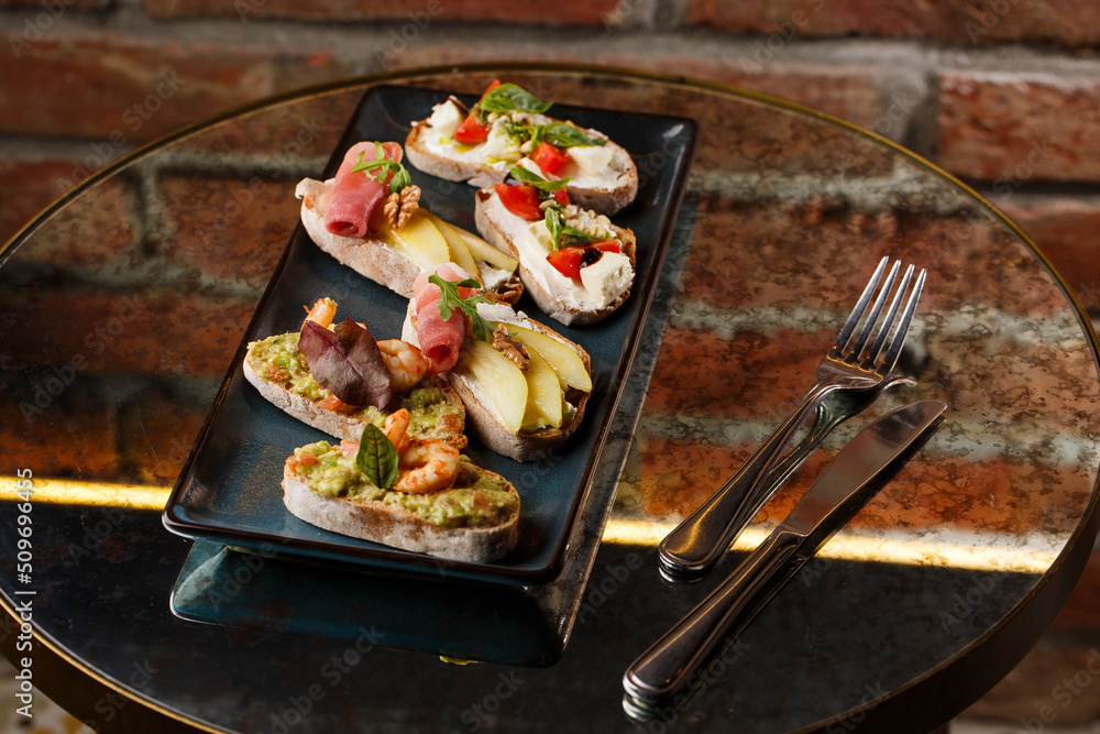 Bruschettas with vegetables. Start dishes with cherry tomatoes, avocado, cream cheese and shrimps. Food composition, tasty italian meal