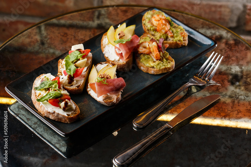Obraz na płótnie Bruschettas with vegetables. Start dishes with cherry tomatoes, avocado, cream cheese and shrimps. Food composition, tasty italian meal w salonie