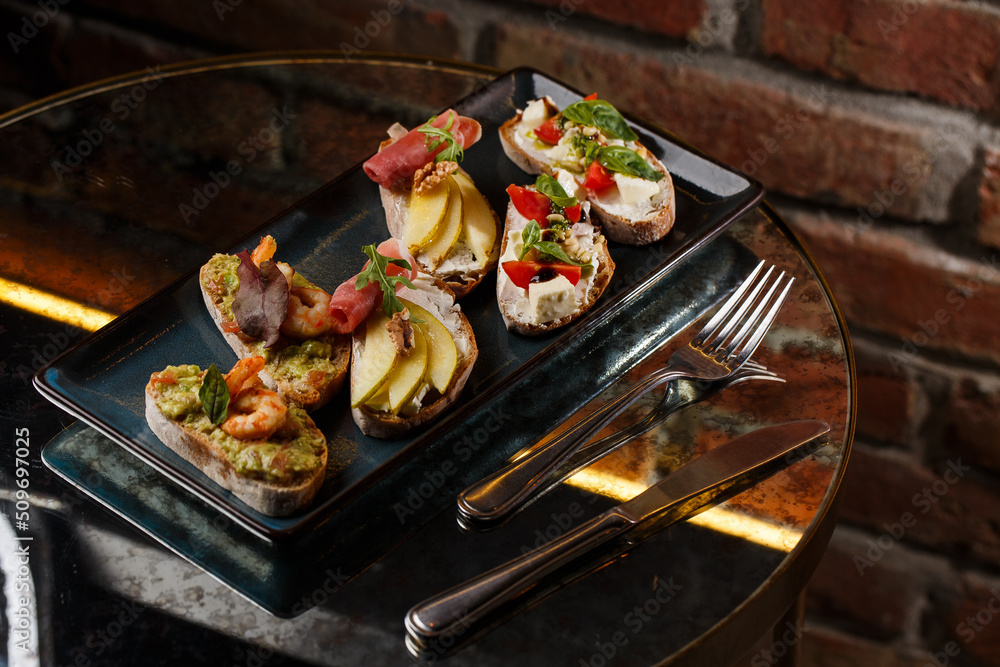 Bruschettas with vegetables. Start dishes with cherry tomatoes, avocado, cream cheese and shrimps. Food composition, tasty italian meal