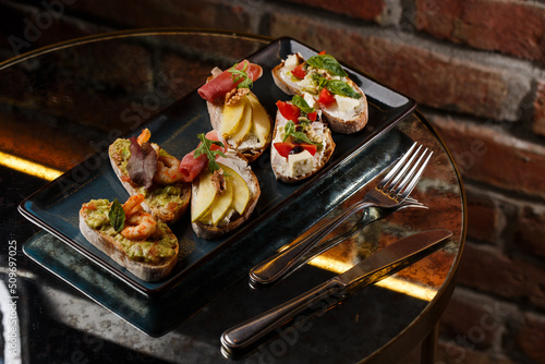 Obraz na płótnie Bruschettas with vegetables. Start dishes with cherry tomatoes, avocado, cream cheese and shrimps. Food composition, tasty italian meal w salonie