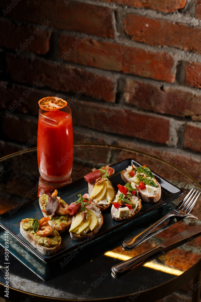 Bruschettas with vegetables. Start dishes with cherry tomatoes, avocado, cream cheese and shrimps. Food composition, tasty italian meal